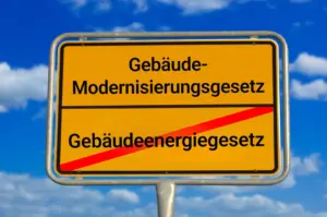 Ortsausgangsschild mit durchgestrichenem Gebäudeenergiegesetz und neuem Schriftzug Gebäudemodernisierungsgesetz.