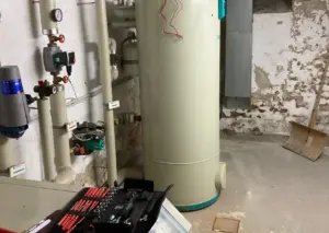 Heizungsanlage im Keller mit Umwälzpumpen und Werkzeug bei der Heizungsreparatur